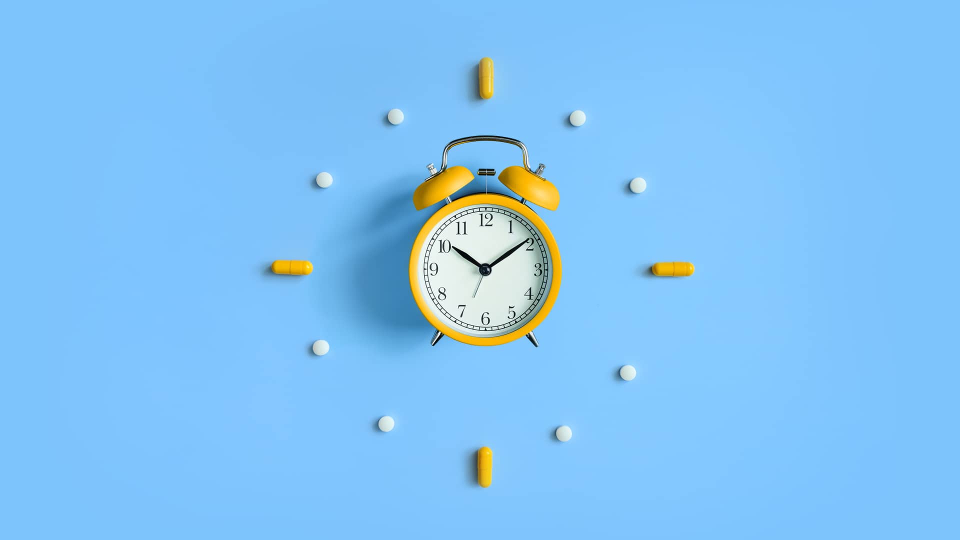 Reloj rodeado de pastillas símboliza el tiempo de carencia desde que se contrata un seguro Adeslas hasta que se puede hacer uso de él