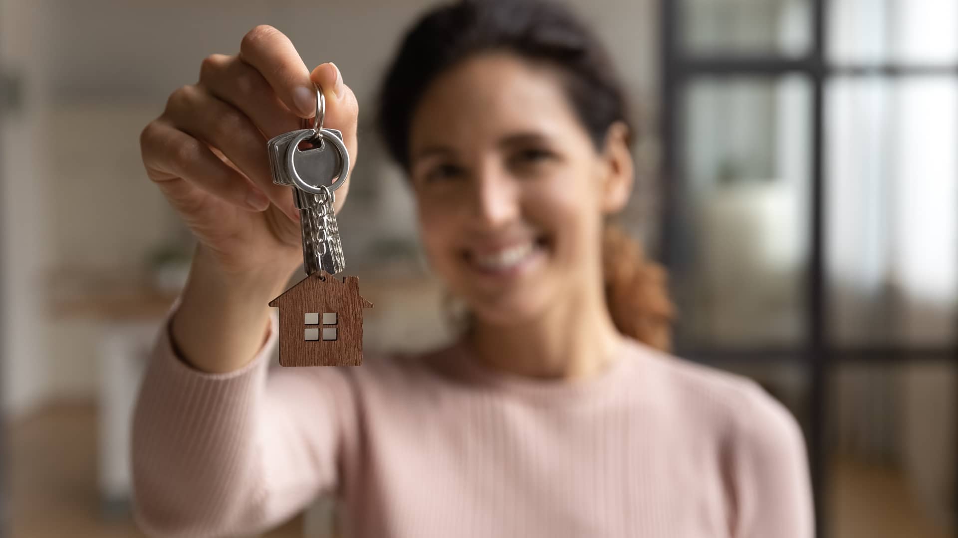 una joven con las llaves de una casa presuminedo de su hogar con seguro de arredamiento de allianz