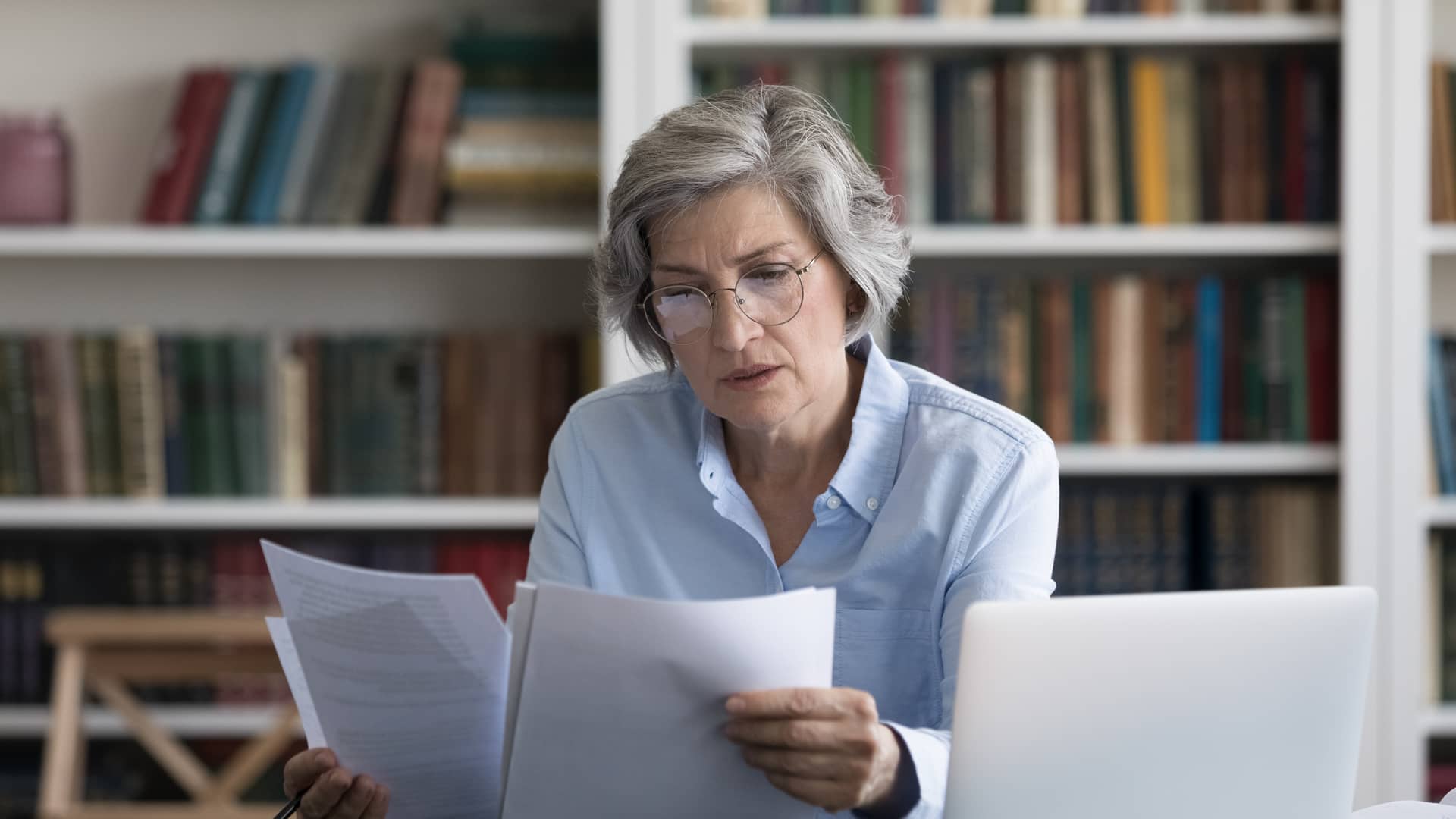 mujer de avanzada edad mirando los papeles de las autorizaciones a unas pruebas medicas con su seguro de asisa