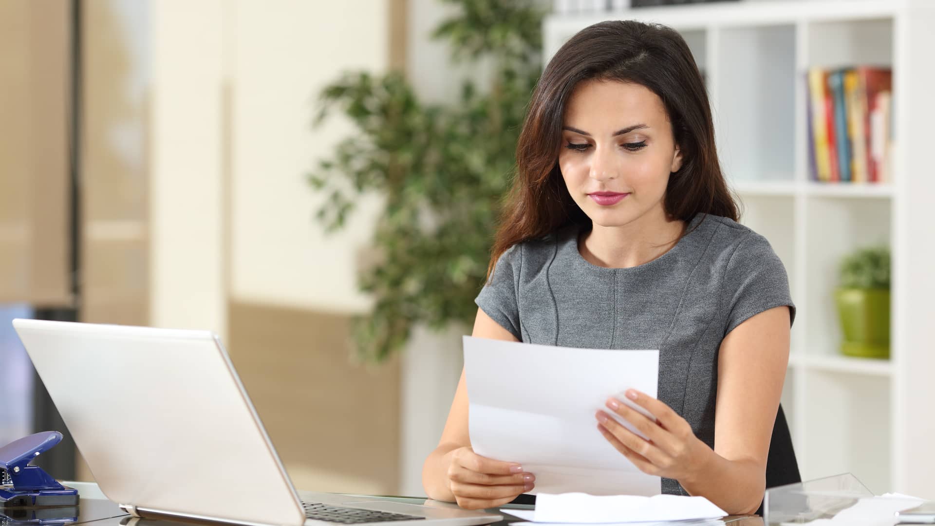 mujer con papeles y un ordenador consultando el precio de los distintos seguros de asisa