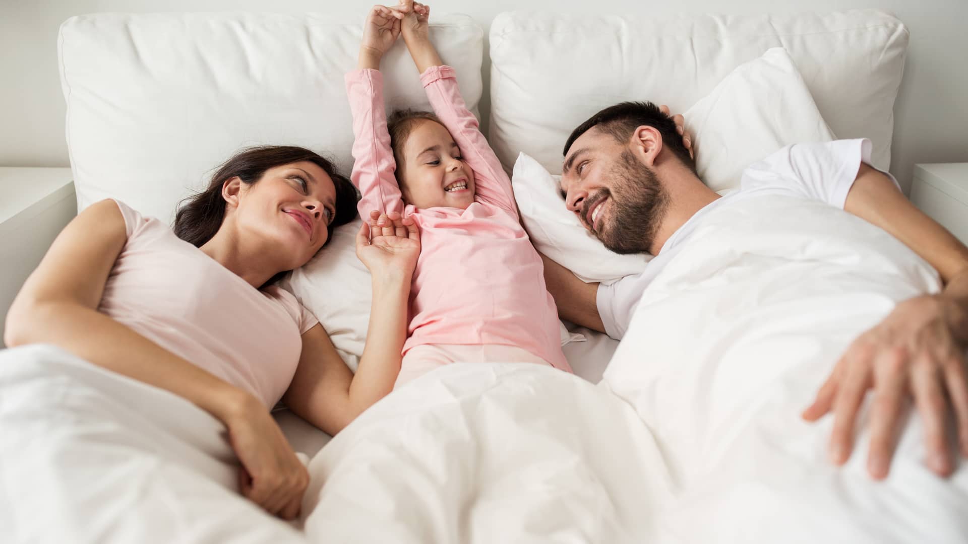 matrimonio tranquilo con su hija en la cama porque tienen un seguro de decesos de proteccion familiar de aura seguros