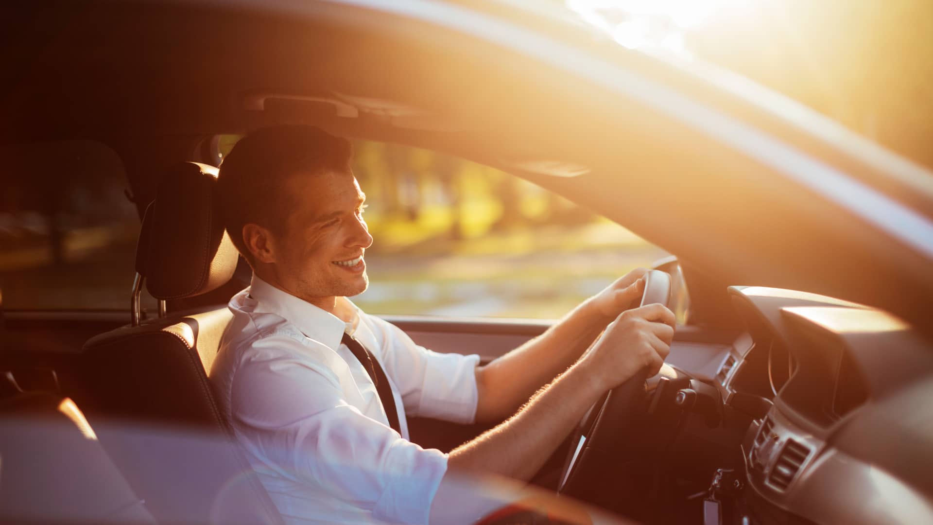 Hombre de negocios sonriente conduciendo su coche con seguro a todo riesgo con axa
