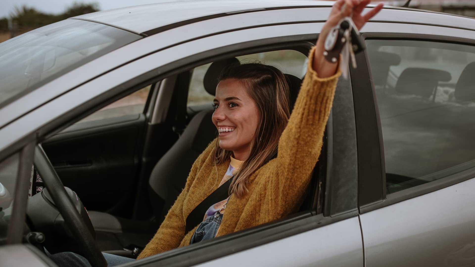 Mujer sonriente en su vehículo asegurado por chapka y con grandes descuentos