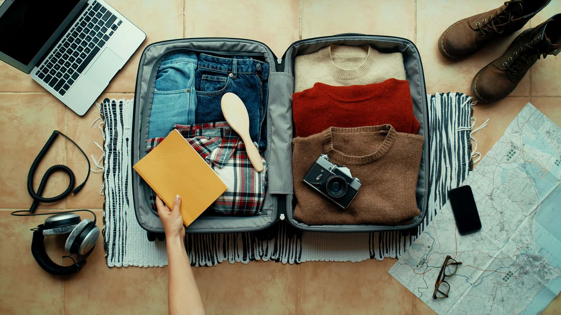 Persona terminando de preparar la maleta para irse de vacaciones con seguro de viaje contratado con heymondo