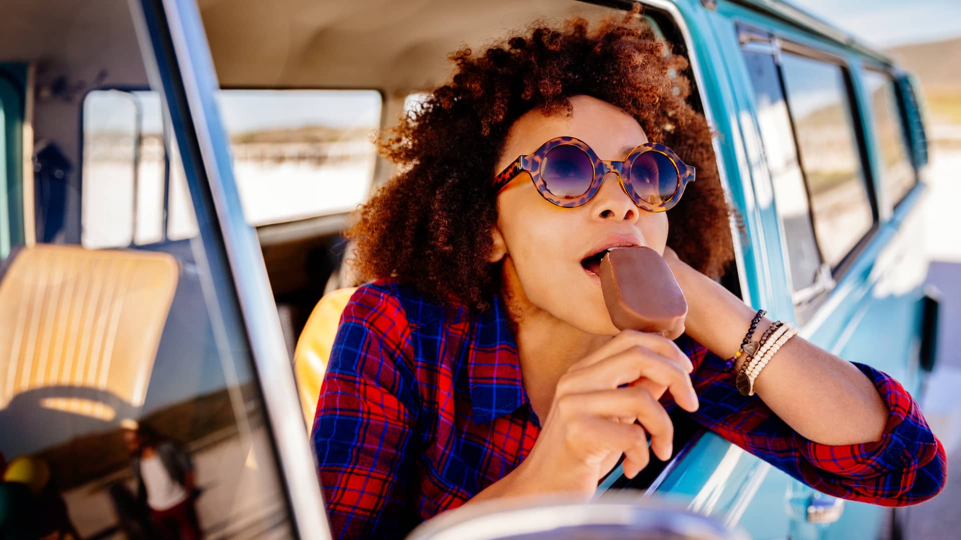 Mujer comiendose un helado por la ventanilla de su coche asegurado con liberty seguros