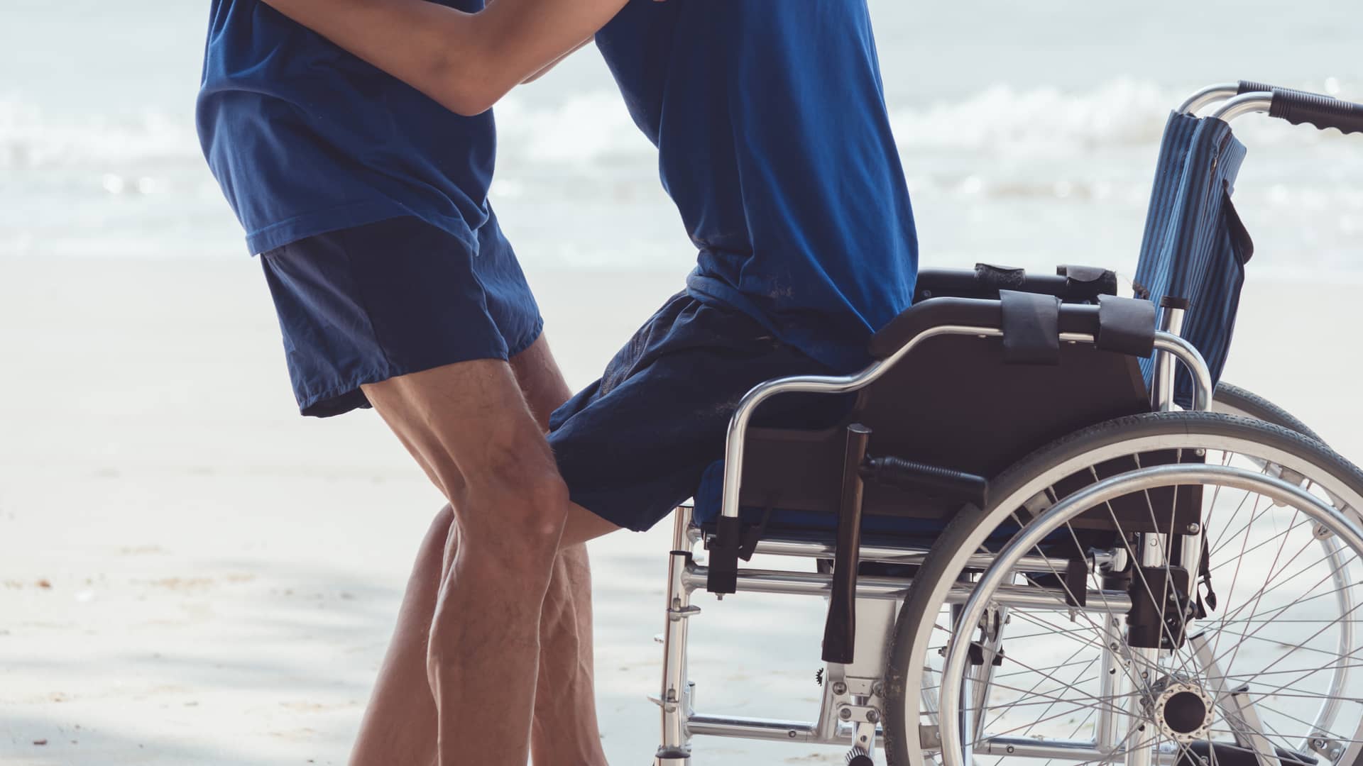 Una persona levantando a un joven de una silla de ruedas que representa el seguro de vida de dependencia de la aseguradora Mapfre