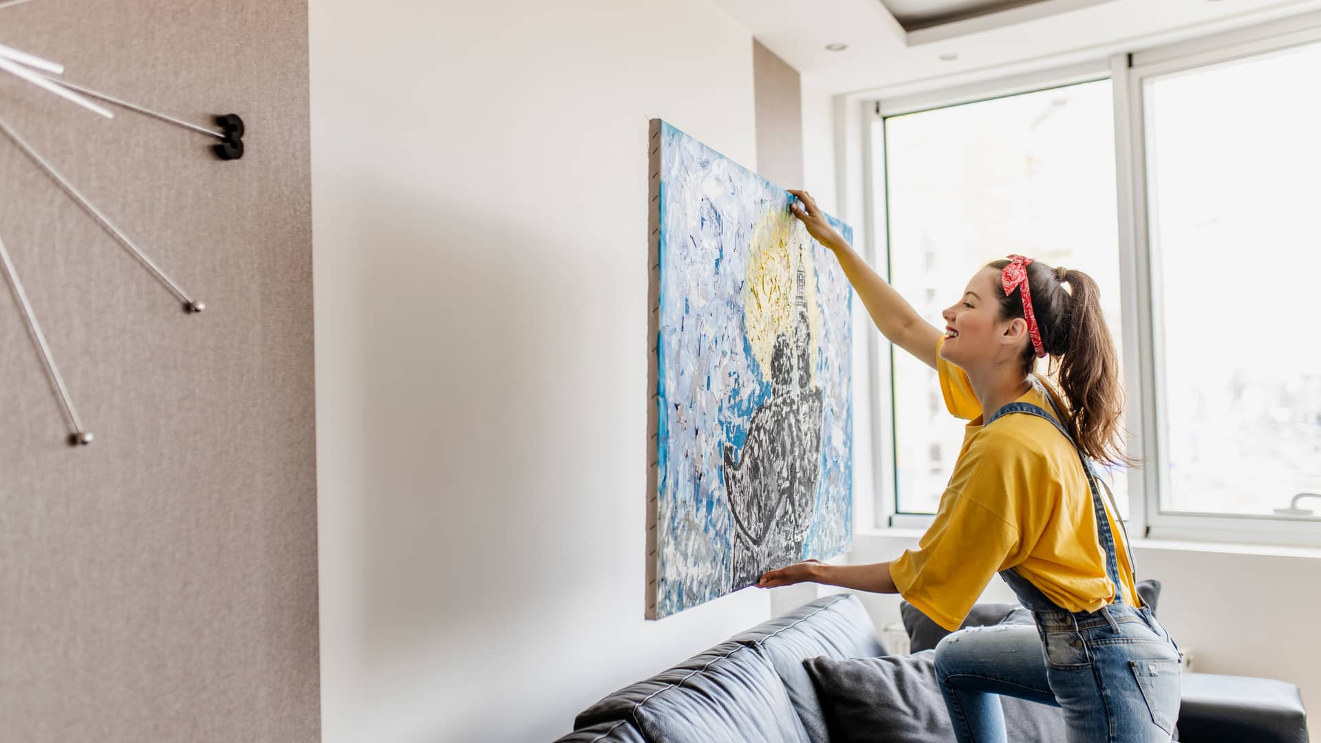 Mujer colocando cuadro en su casa con seguro de hogar con mgs