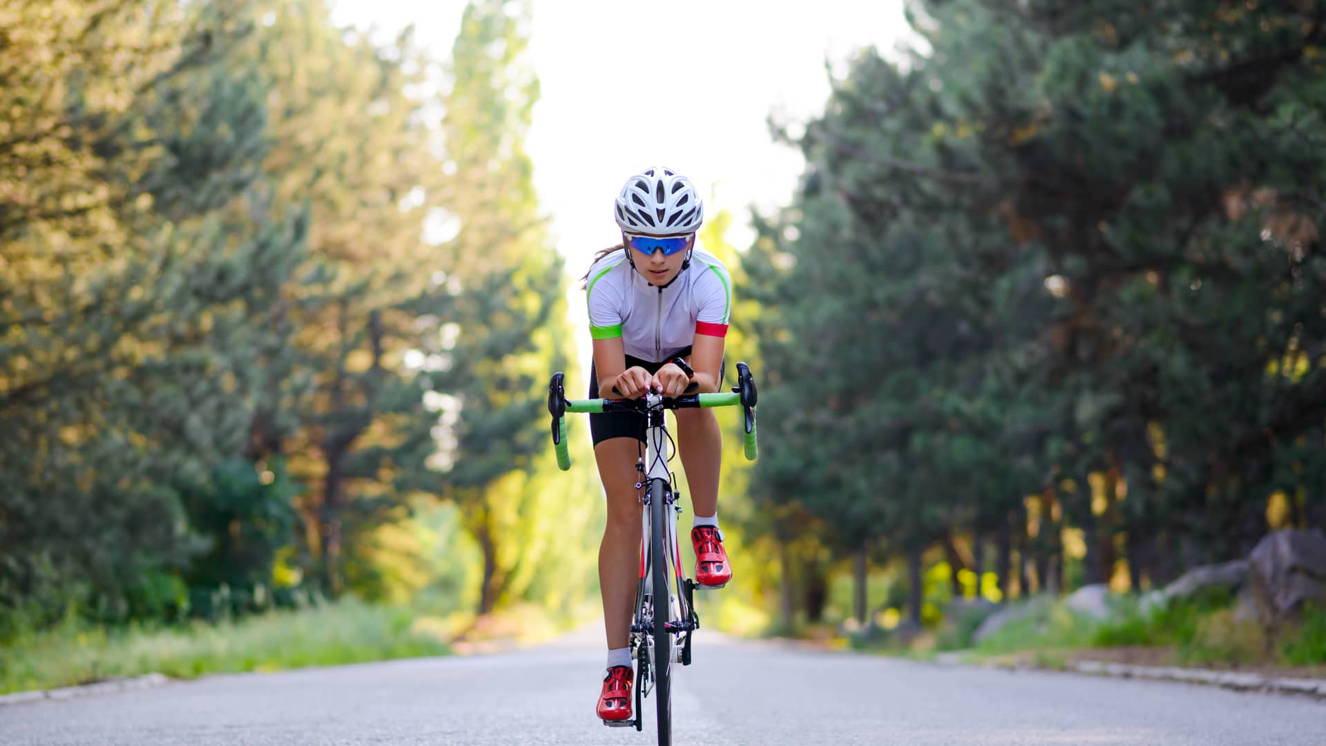 Una joven montando en bicicleta en una carretera de bosque sin seguro para ese deporte en la Mutua Madrileña