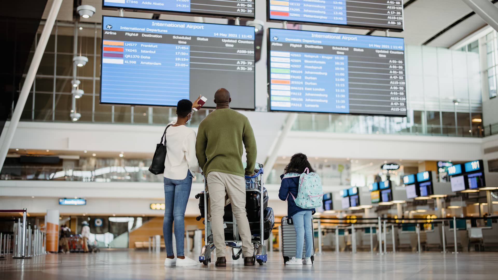 Una familia de espaldas en el aeropuerto que se va de vacaciones con su seguro de viajes de la Mutua Madrileña