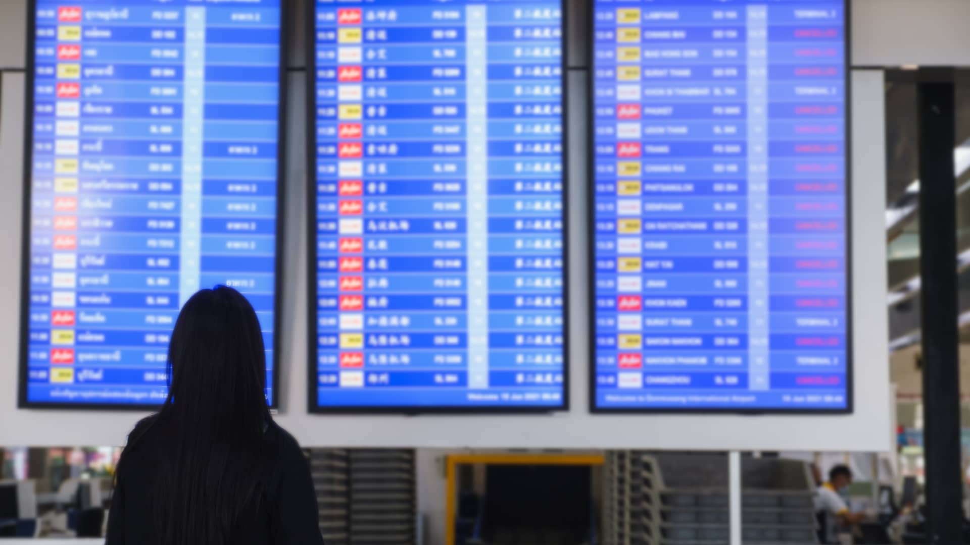 Una turista mirando las pantallas de un aeropuerto bien informada por el área de clientes de Sanitas