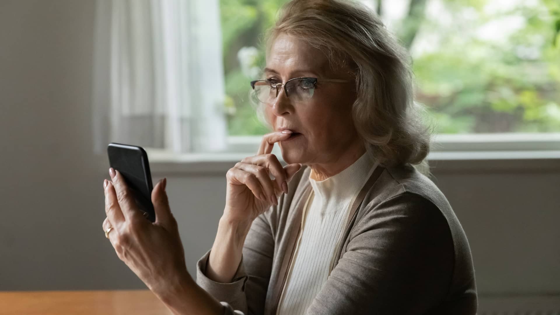 Mujer de avanzada edad solicitando con su teléfono móvil una autorización en Sanitas