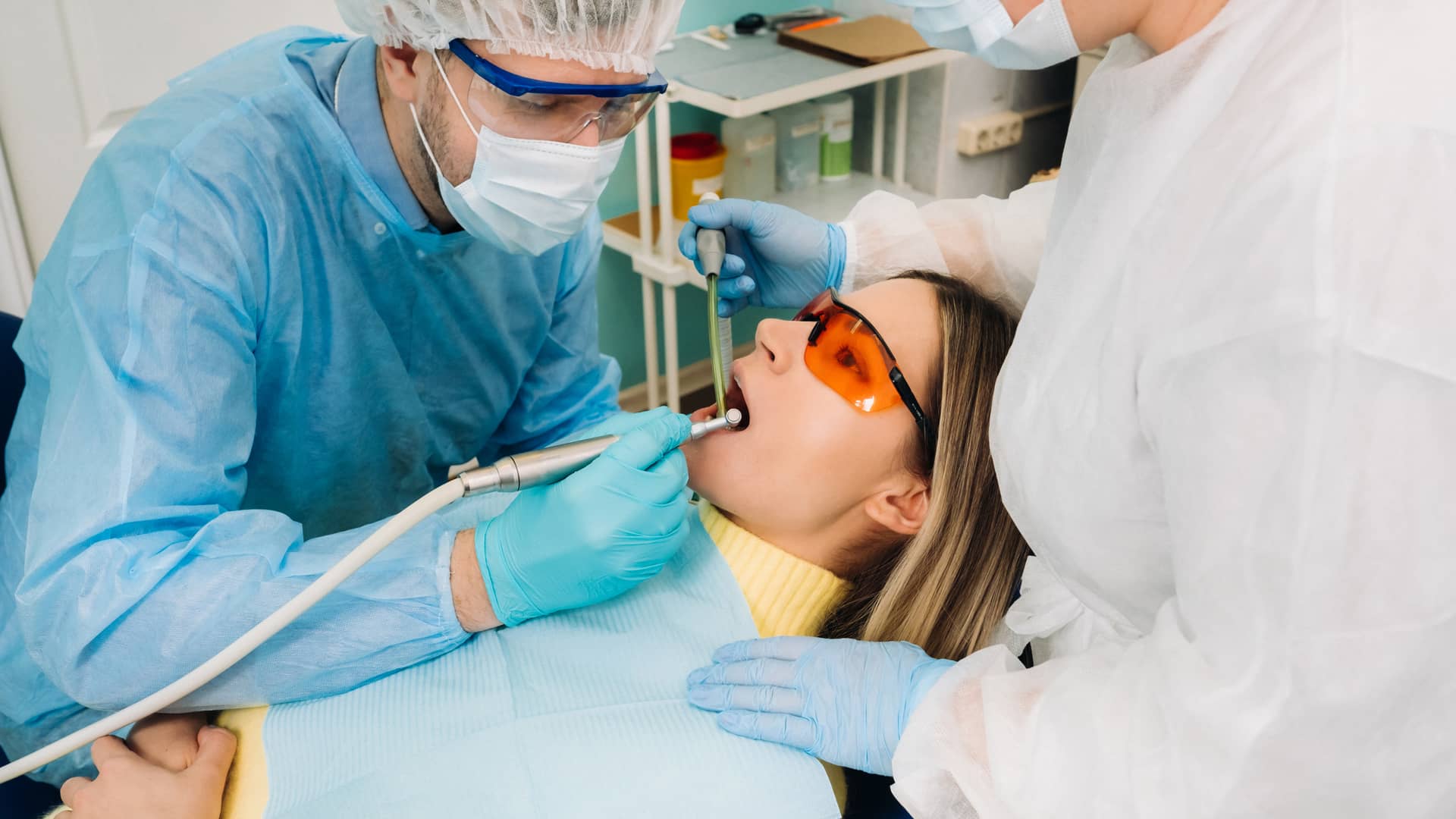 Chica joven siendo atendida por dos dentistas del cuadro médico de Sanitas