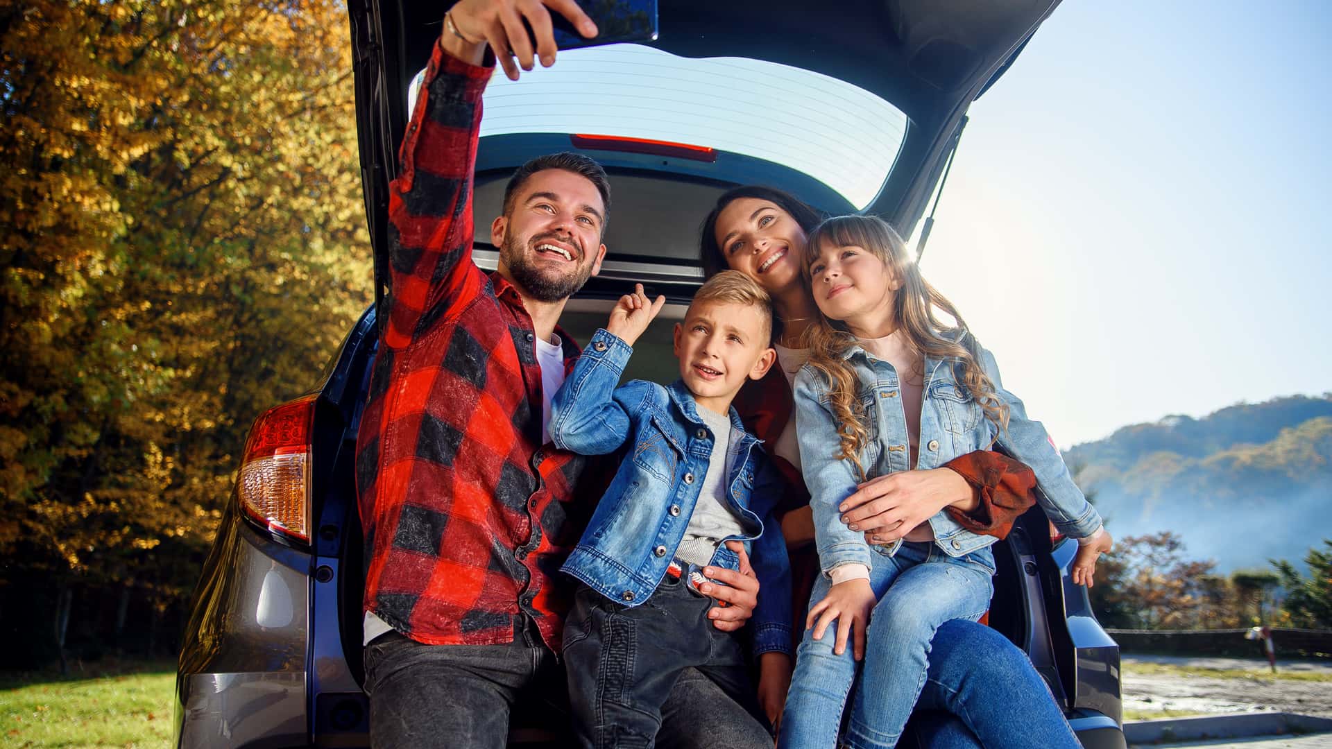 Familia sentada en el maletero de su coche asegurado con verti haciendose una foto