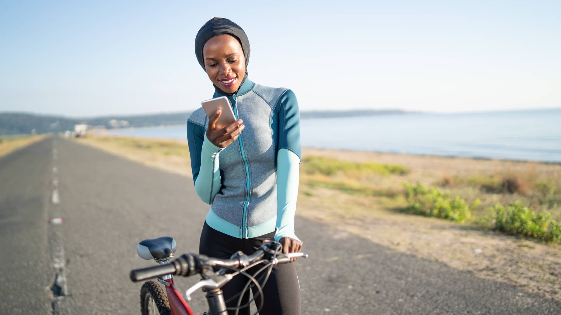 Mujer buscando en su teléfono el número de asistencia del seguro de su bicicleta