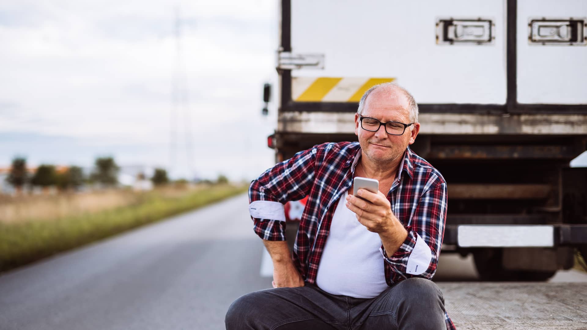 Camionero con su teléfono realizando llamada a sus seguro para  recibir asistencia en carretera