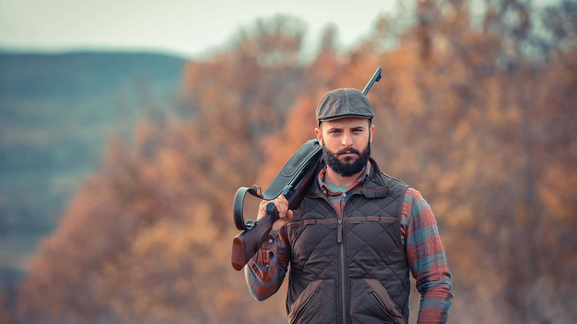 Hombre joven y seguro con escopeta con seguro de caza de tiro deportivo