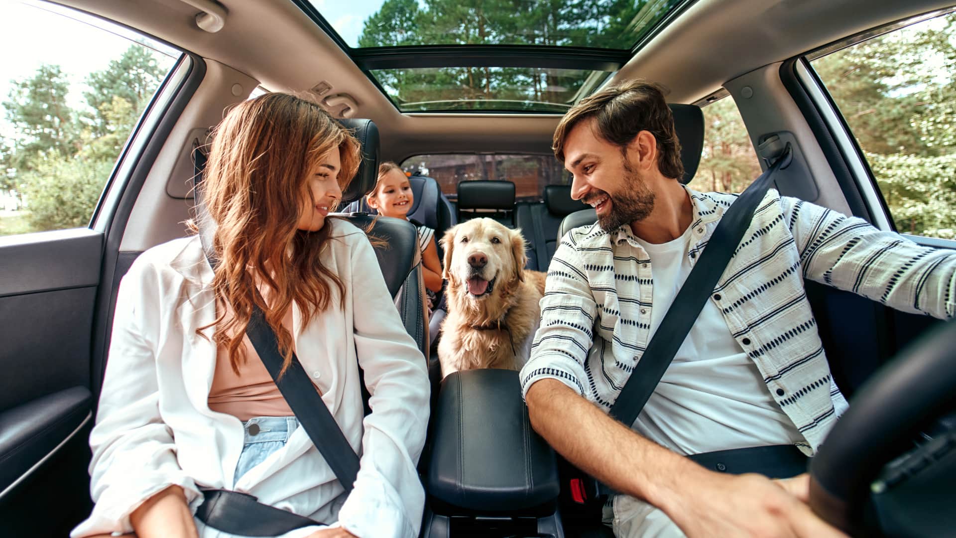 Familia de viaje en su coche alegres y sonrientes con seguro de coche barato contratado