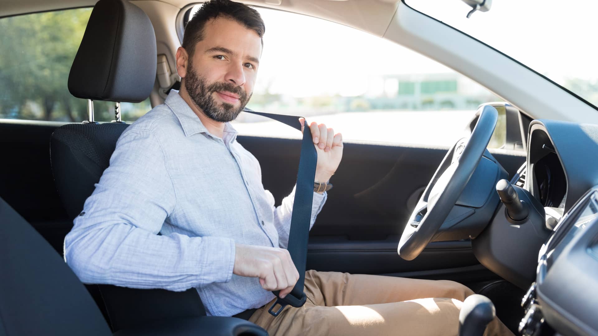 Hombre coclocandose cinturón de seguridad en su coche con seguro con franquicia