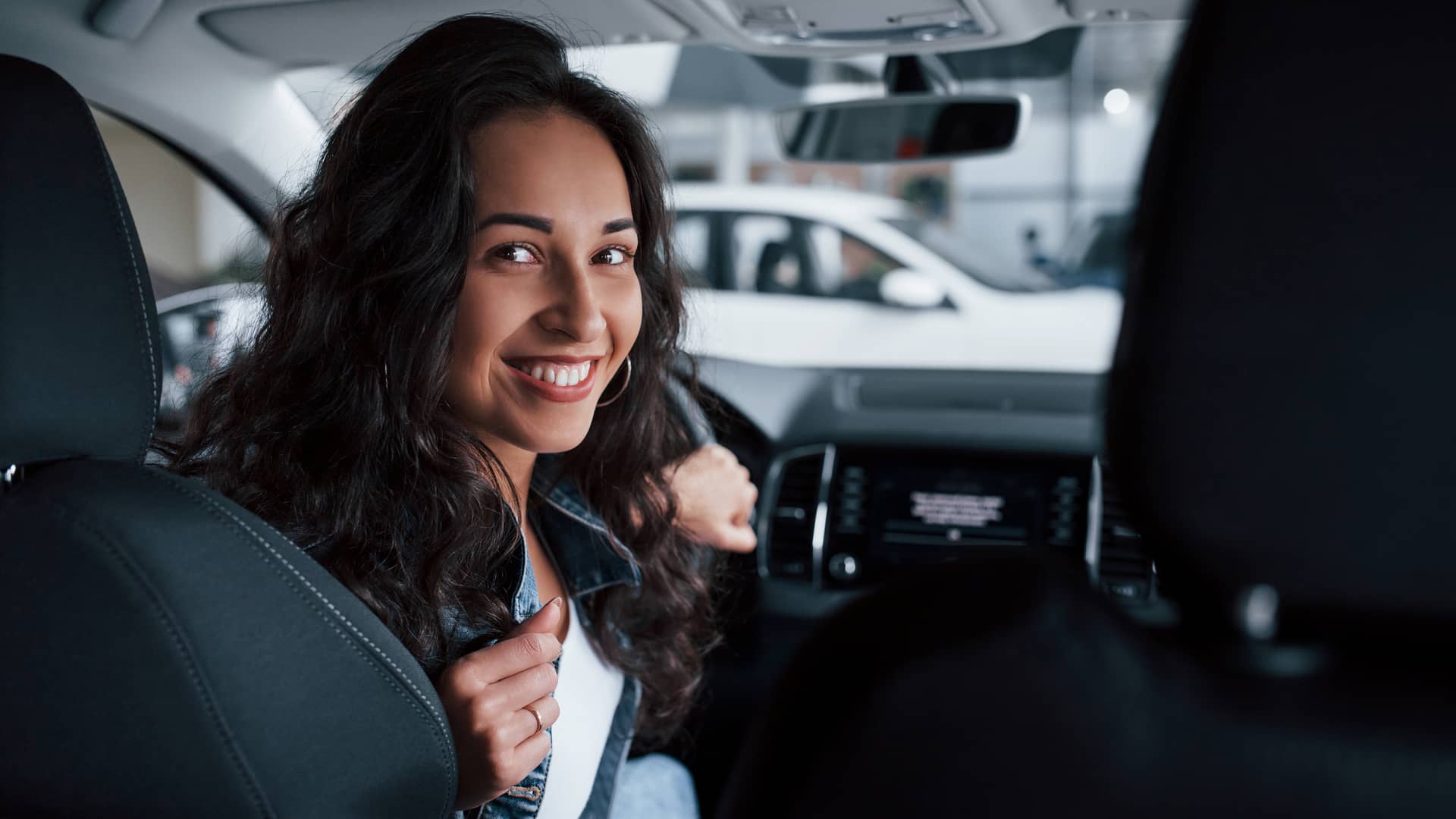 Mujer sonriente en su coche con seguro con coberturas especiales para mujeres