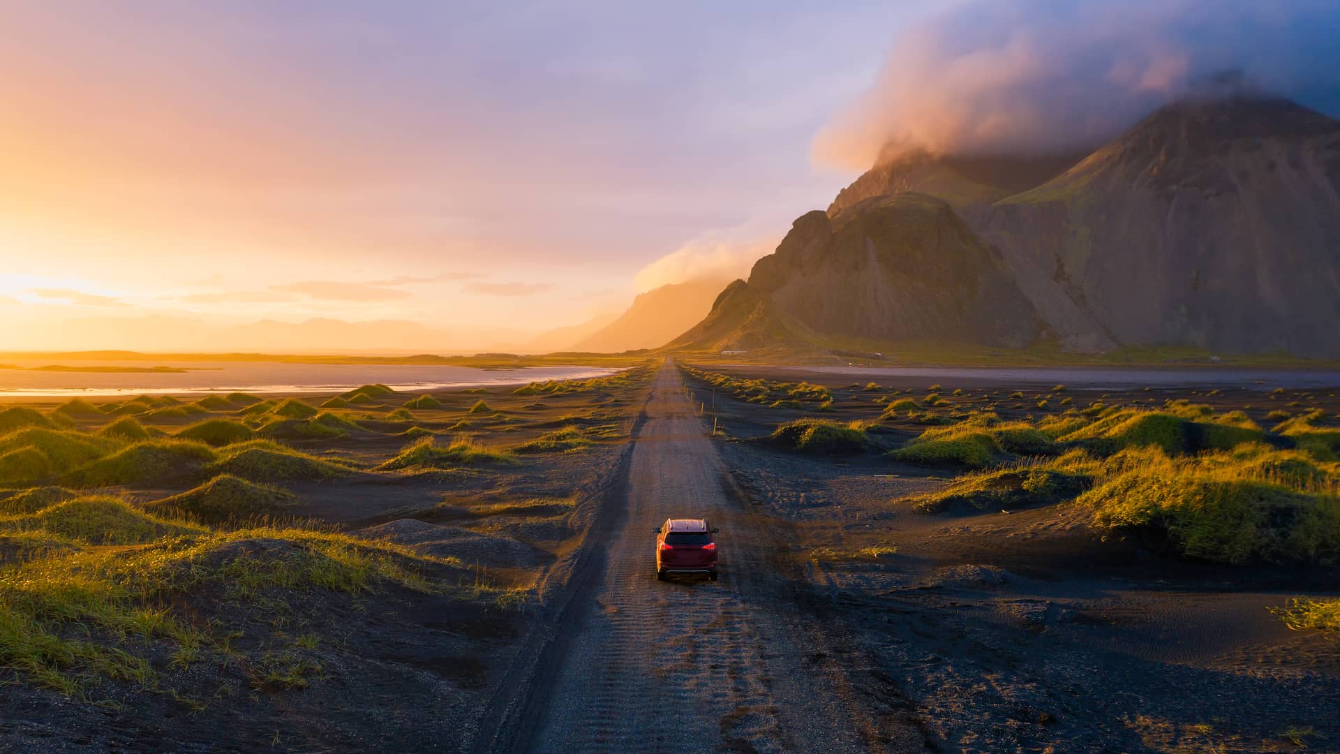 Persona conduciendo su coche hacia montaña con volcán cuyo seguro cubre de riesgos extraordinarios