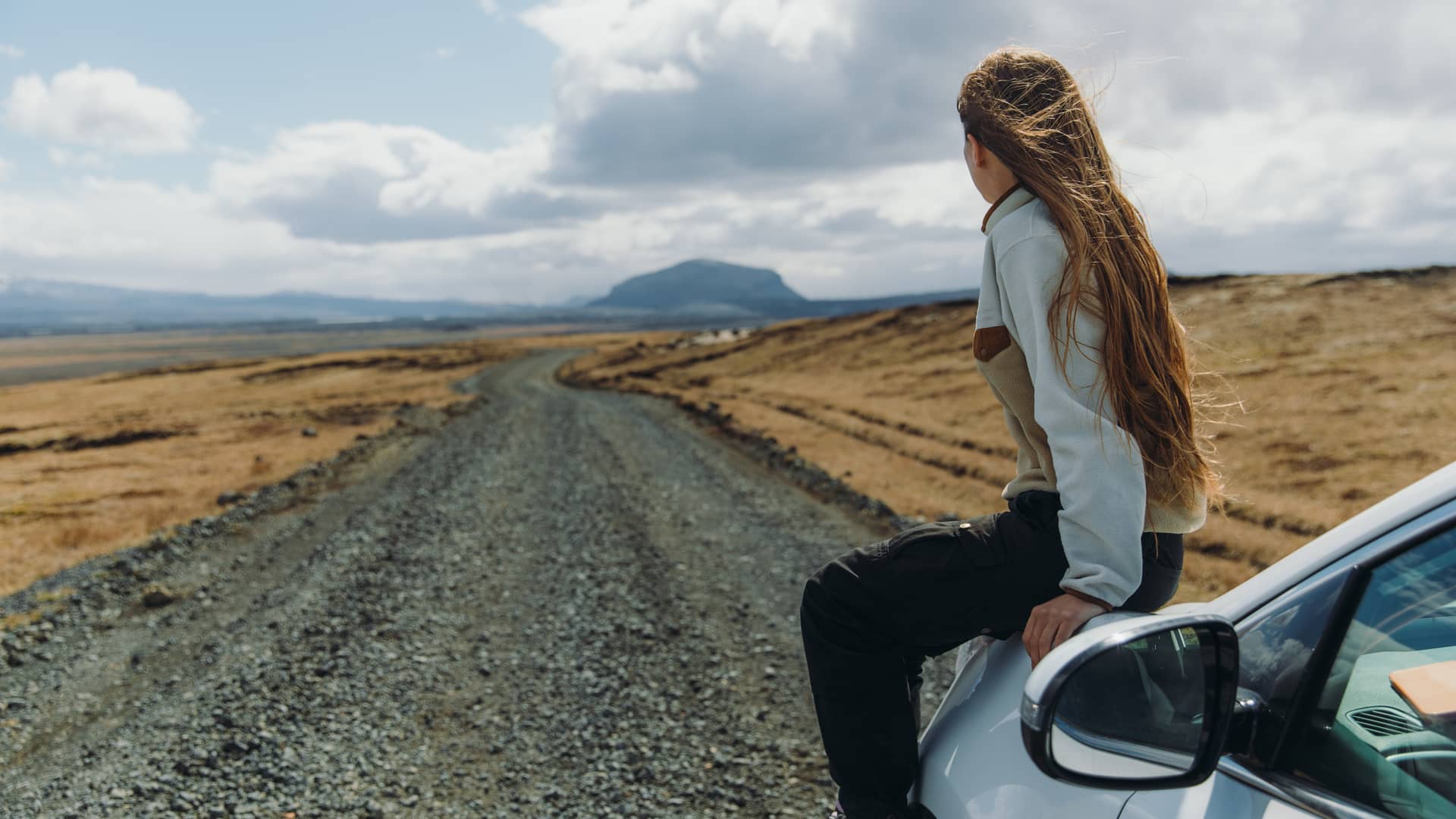 Mujer con su coche de viaje por Islandia con un seguro para coche en el extranjero contratado