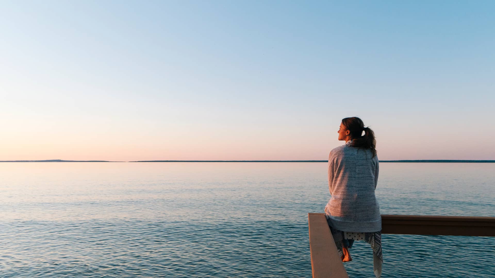 Mujer que ha hecho un pago único por su seguro de decesos viendo el atardecer a orilla del mar