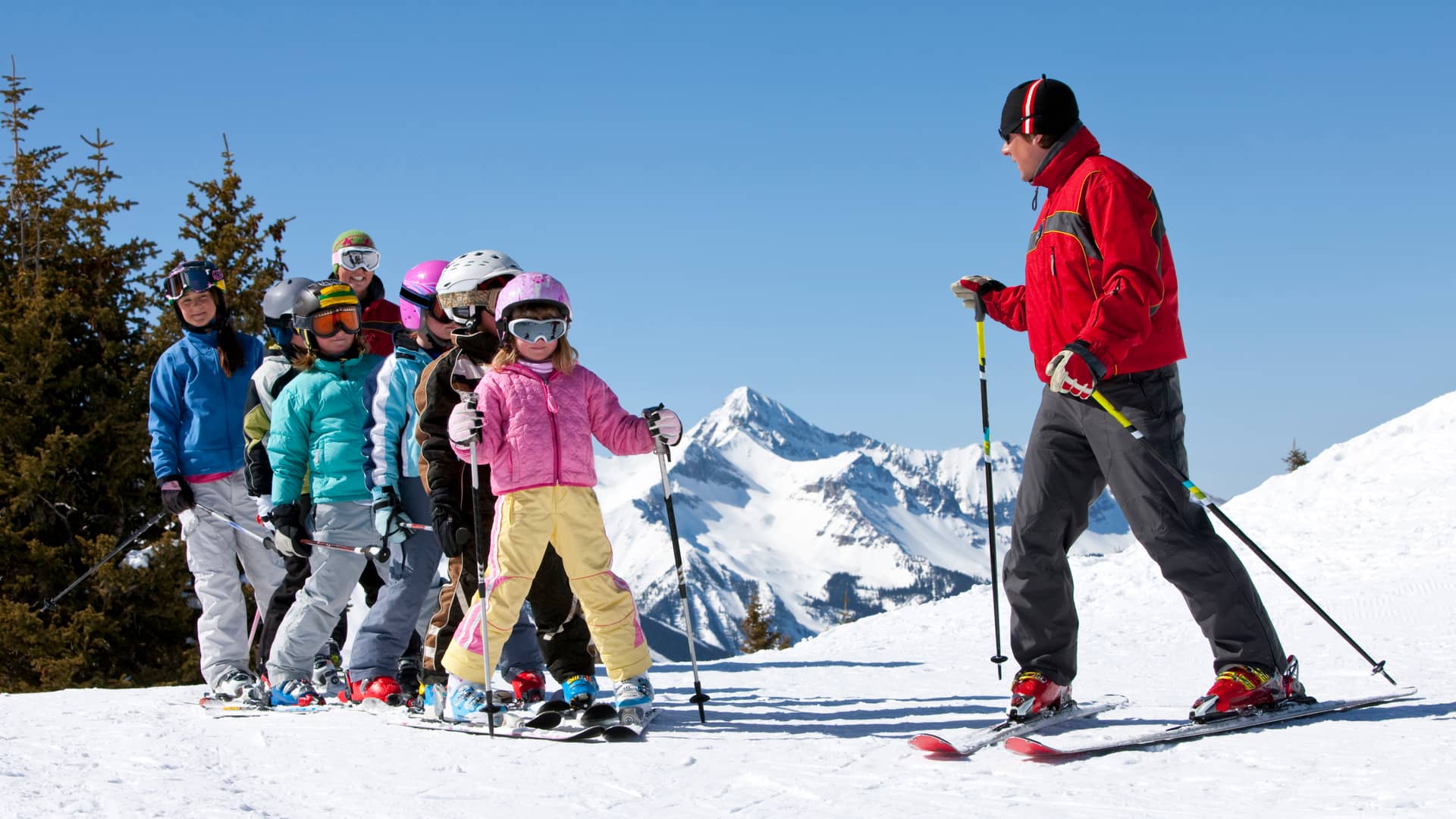 Profesor de esquí con seguro enseñando a niños 