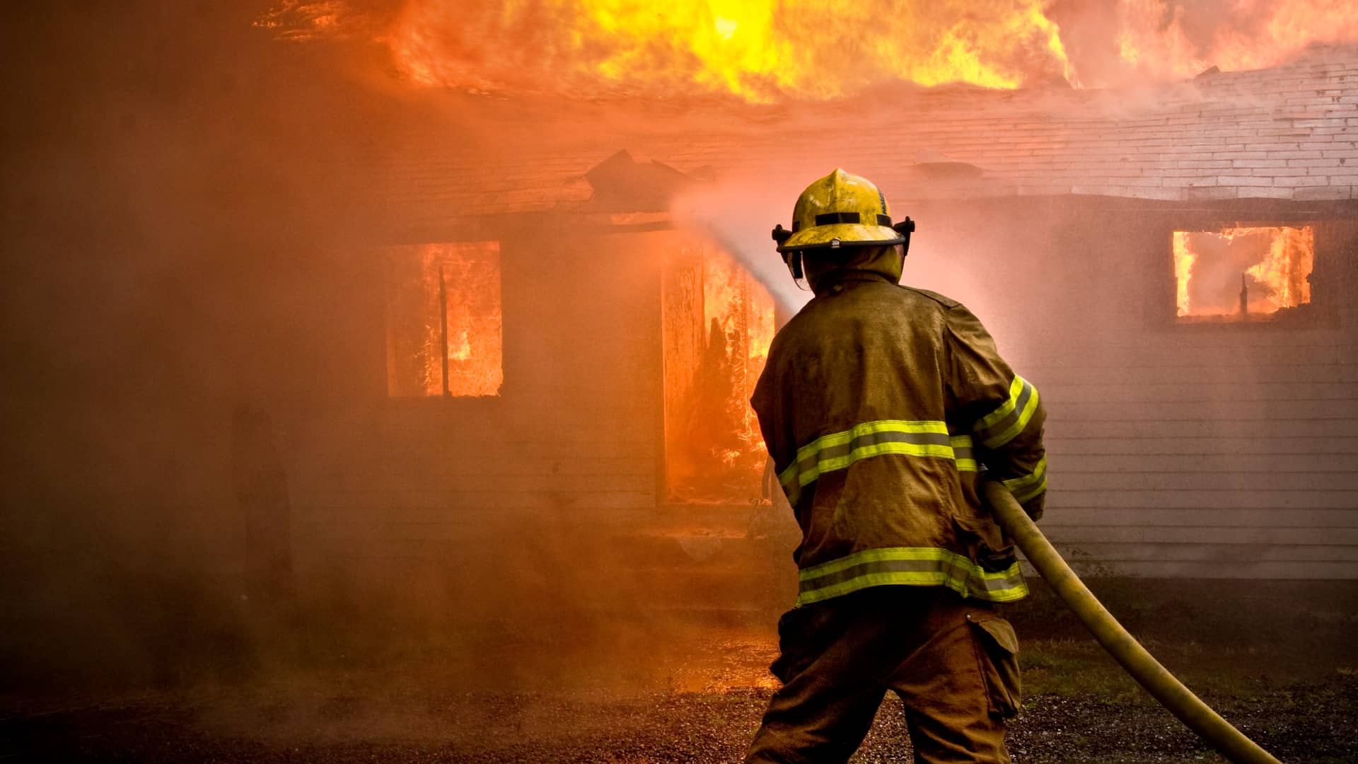 Bombero sofocando incendio en hogar con seguro de incendio