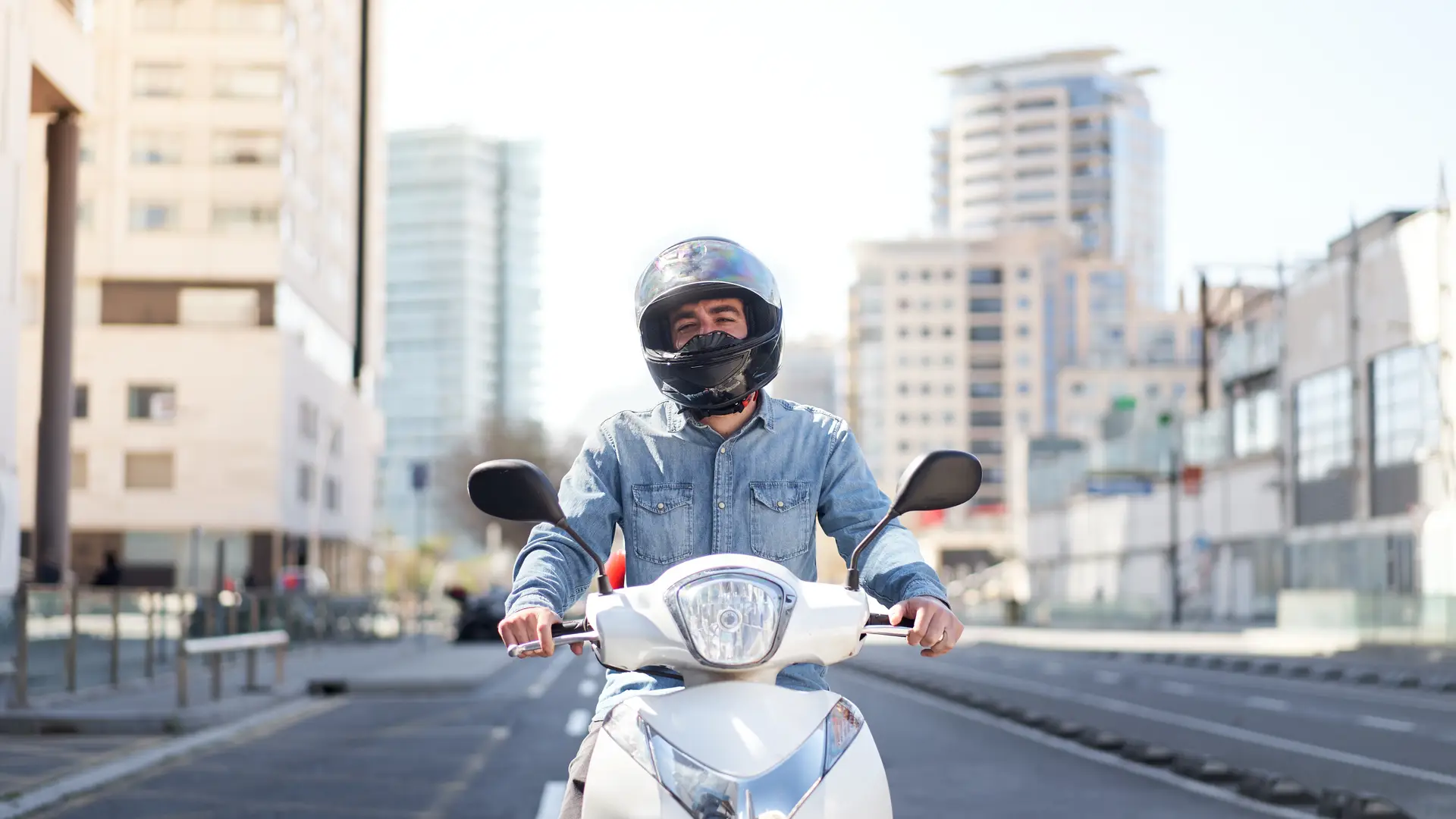 Un joven con el casco y la moto que busca un seguro de motos barato