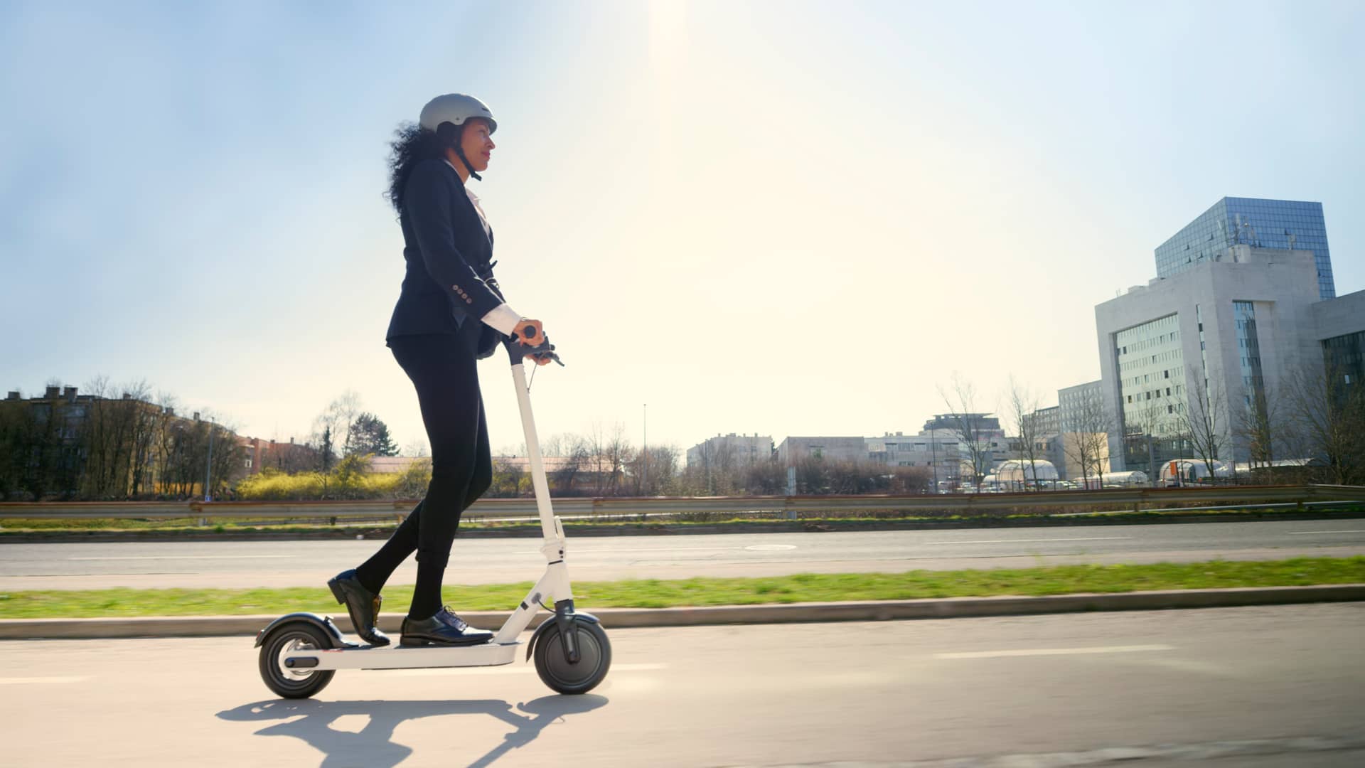 Mujer circulando por ciudad con patinete eléctrico de alquiler con seguro con unas mínimas coberturas
