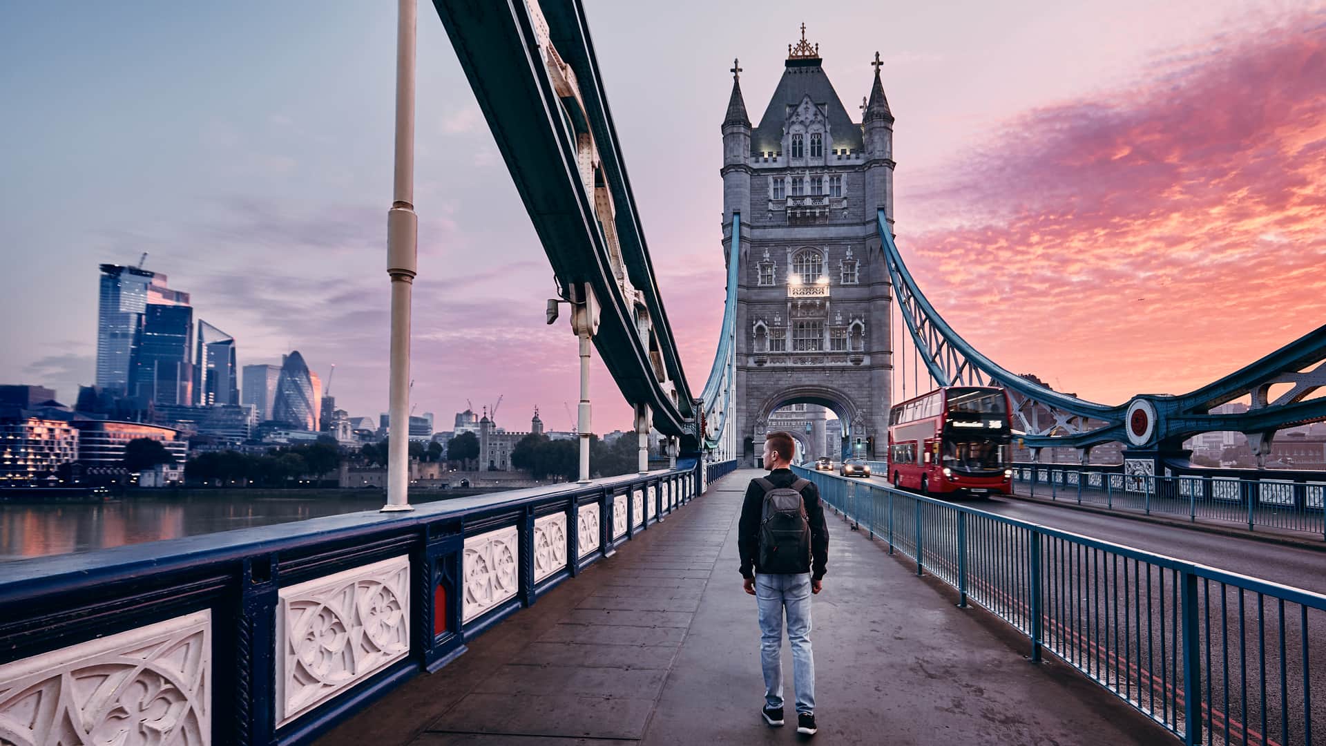 Joven paseando por puente de Londres con seguro de viaje para el Reino Unido contratado