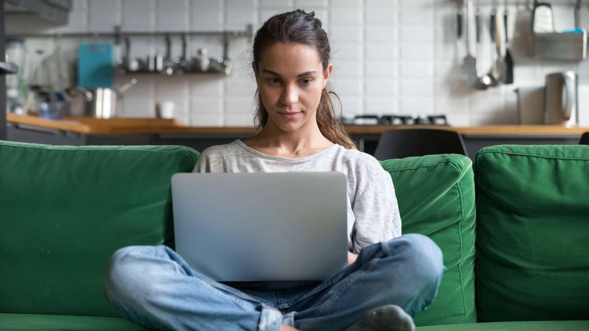 Una chica seria con el ordenador en el sofa mirando como hacer un exorto sin penalizaciones con su aseguradora