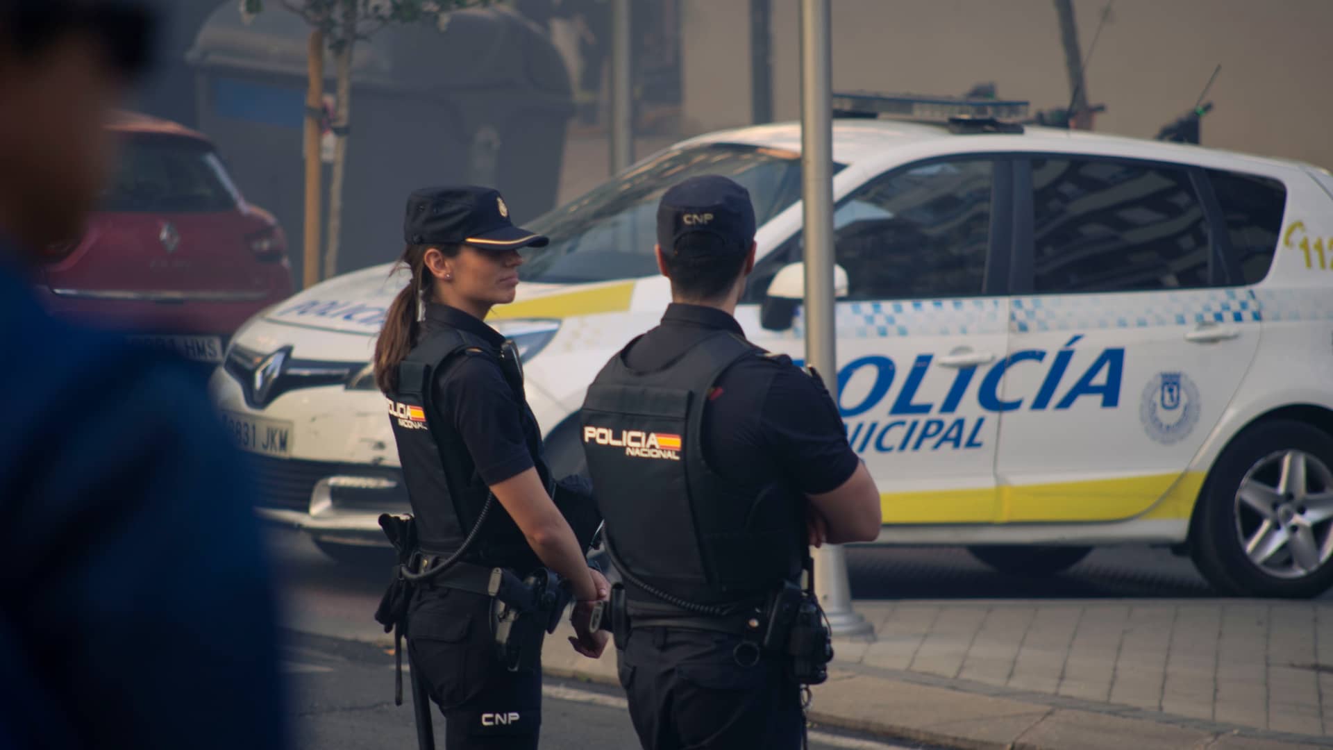 Dos operarios de la policia Nacional delante de un coche que estan tranquilos porque tienen un seguro especial para policias